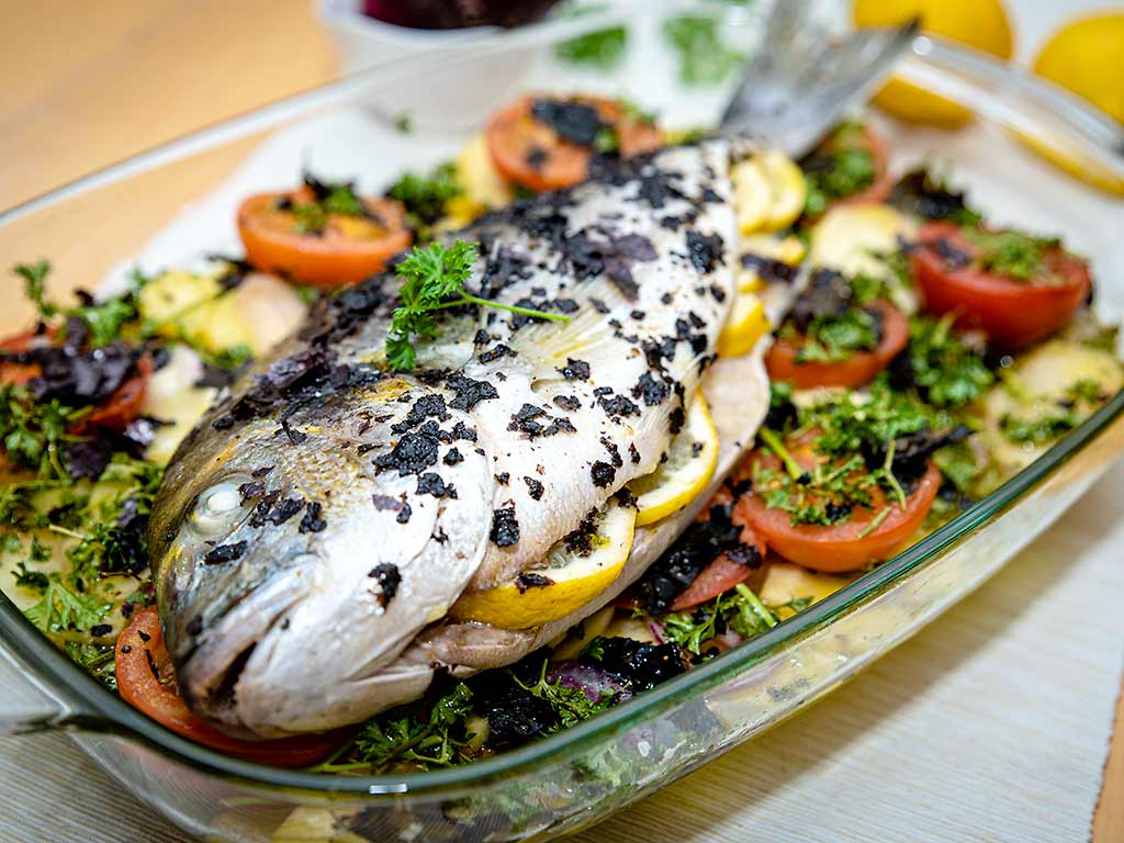 Foto einer im Ofen gebackenen Dorade auf Gemüse mit Algen