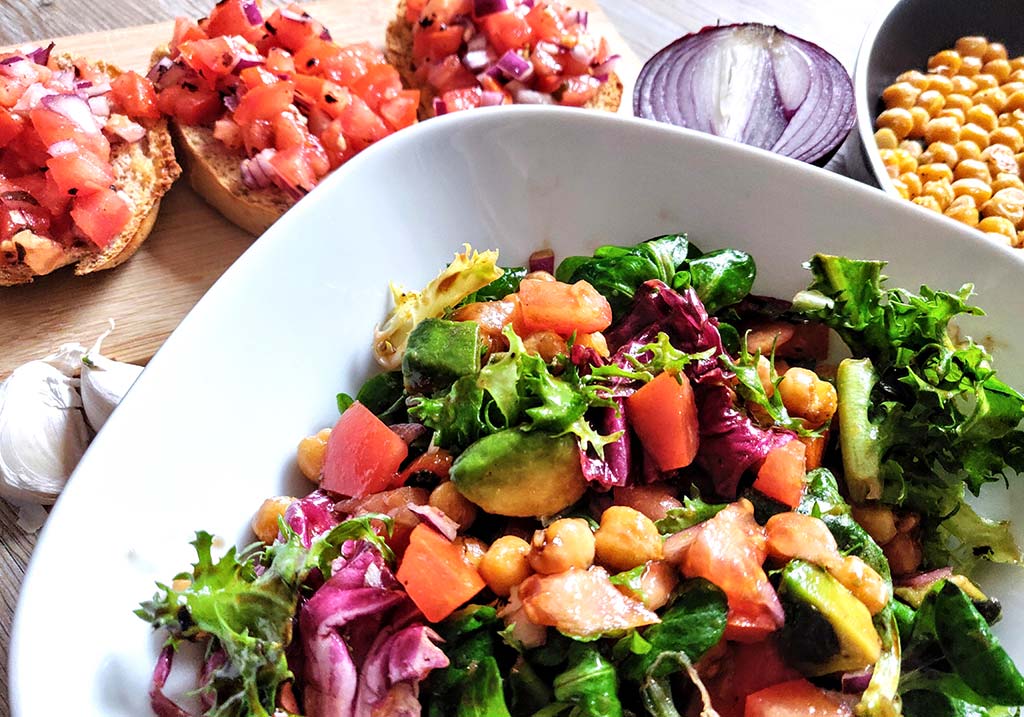 Foto einer Schüssel Salat und Bruschetta am Holztisch